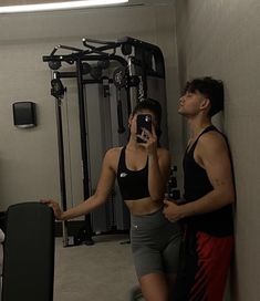 a man and woman taking a selfie in the mirror with their cell phones while standing next to each other