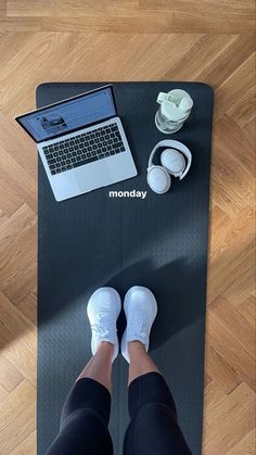 a person standing on a yoga mat with their feet propped up in front of a laptop