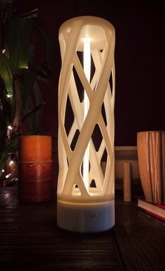 a white lamp sitting on top of a table next to a potted plant and books