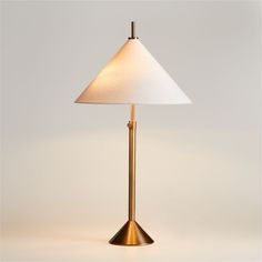 a lamp with a white shade on top of it and a gold metal pole underneath