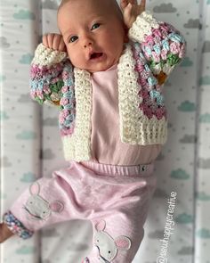 a baby is laying on its back in a crochet outfit and holding it's head up