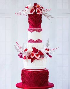 a red and white wedding cake with flowers on top