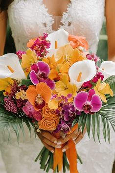 a bride holding a bouquet of orchids and calla lilies in her hands