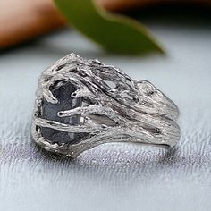 a silver ring sitting on top of a table next to a leafy green plant