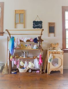 a wooden shelf with clothes hanging on it in a room filled with windows and other items