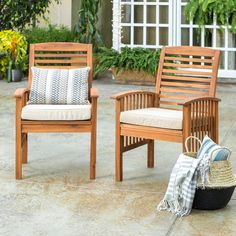 two wooden chairs sitting next to each other on top of a cement floor covered patio