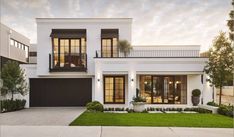 a white two story house with lots of windows and grass on the front lawn area