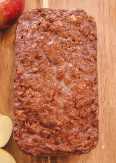 a loaf of bread sitting on top of a wooden cutting board next to an apple