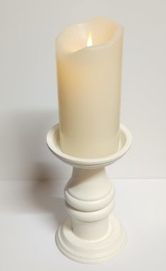 a white candle sitting on top of a pedestal