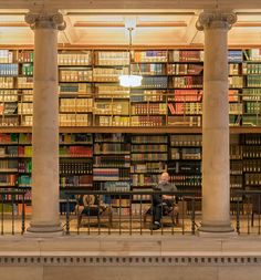 a man sitting on a bench in front of a library full of books