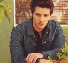 a man sitting at a table in front of a plant