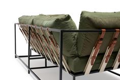 two green couches sitting next to each other in front of a metal frame with leather straps