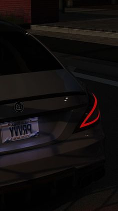 the back end of a black car with red lights on it's license plate