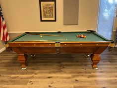 a pool table in a room with an american flag hanging on the wall behind it