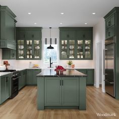 a large kitchen with green cabinets and wood flooring, along with stainless steel appliances