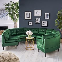 a living room with green couches and pictures on the wall above it, along with a round coffee table