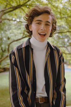 an instagram photo of a young man with curly hair wearing a black and white striped jacket