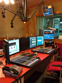 a control room with multiple monitors and two microphones on the desk in front of them