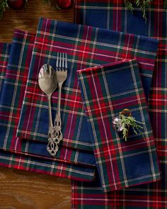 a plaid table cloth with a fork and knife on it, next to christmas decorations