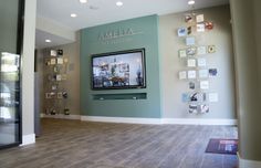 a large television mounted to the side of a wall next to a wooden floor in front of a glass door