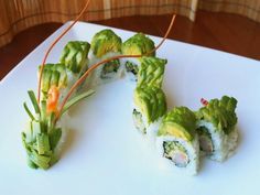 a white plate topped with sushi and veggies on top of each other