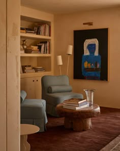 a living room with two blue chairs and a coffee table in front of a book shelf