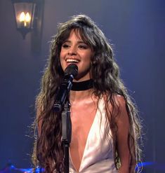 a woman standing in front of a microphone with long hair and wearing a halter top