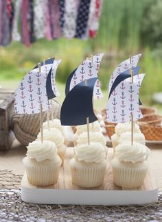 cupcakes with sailboats on them sitting on a table