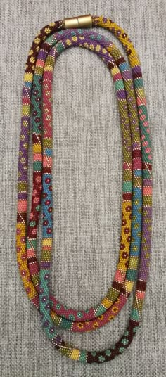 multicolored beaded necklace with gold clasp on grey fabric background, close up