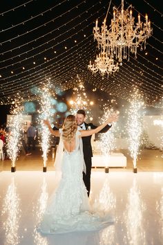 a bride and groom are dancing on the dance floor with sparklers all around them