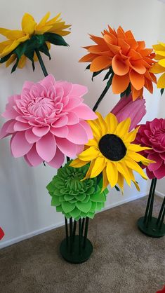 colorful paper flowers are arranged in vases on the floor