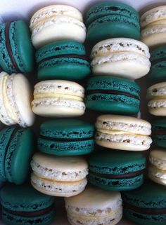 a box filled with green and white macaroons on top of eachother