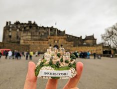 someone holding up a small castle shaped magnet