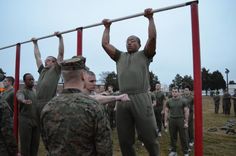 men in army fatigues are doing pull ups