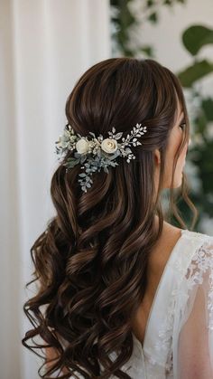 a woman with long brown hair wearing a white flower and leaf bridal headpiece