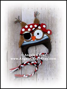 a crocheted owl hat with red and white polka dots on it, sitting on top of a wooden floor