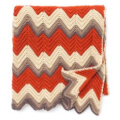 a crocheted dishcloth with an orange and white zigzag pattern