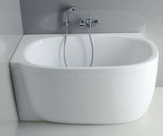 a white bath tub sitting next to a toilet in a bathroom under a faucet