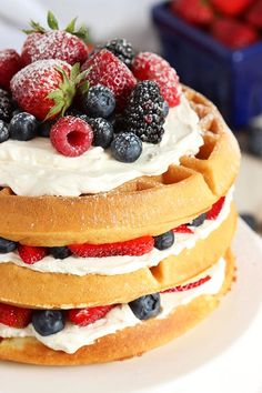 a stack of waffles topped with berries and whipped cream