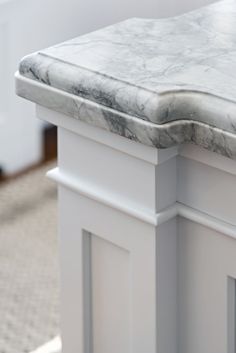 a marble topped table in a room with carpeted flooring and white walls behind it