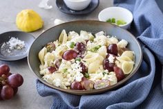 a bowl filled with pasta, grapes and cheese