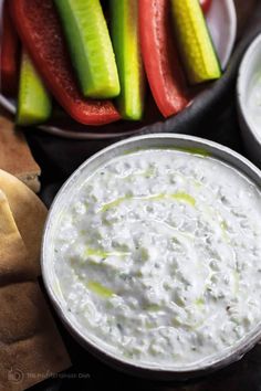 dip with celery, cucumbers and pickles in bowls on a table