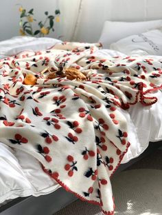 an unmade bed with white sheets and red cherries on it