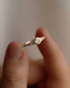 a close up of a person's hand holding a ring with a diamond on it