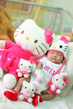 a baby laying on top of a bed next to stuffed animals