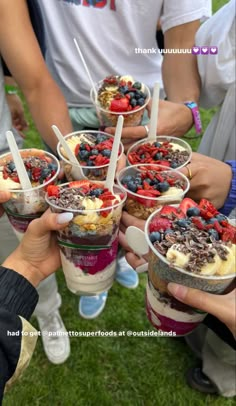 people are holding up cups with desserts in them