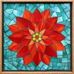 a red flower sitting on top of a blue and green tile covered wall next to a wooden frame