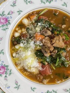 a bowl of soup with meat, vegetables and parmesan cheese in it on a floral plate