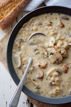 a bowl of soup with meat and mushrooms in it next to a piece of bread