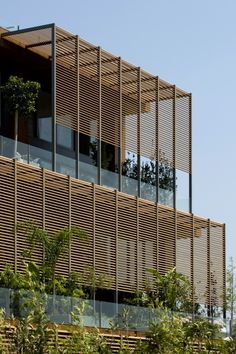 a tall building with wooden slats on it's sides and trees in the foreground